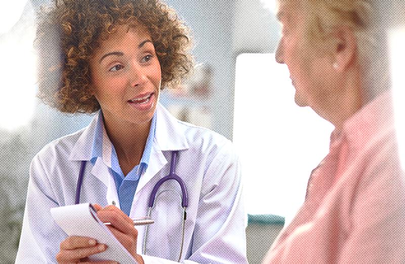 A doctor writes on a notepad while discussing the PureWick™ System with her patient